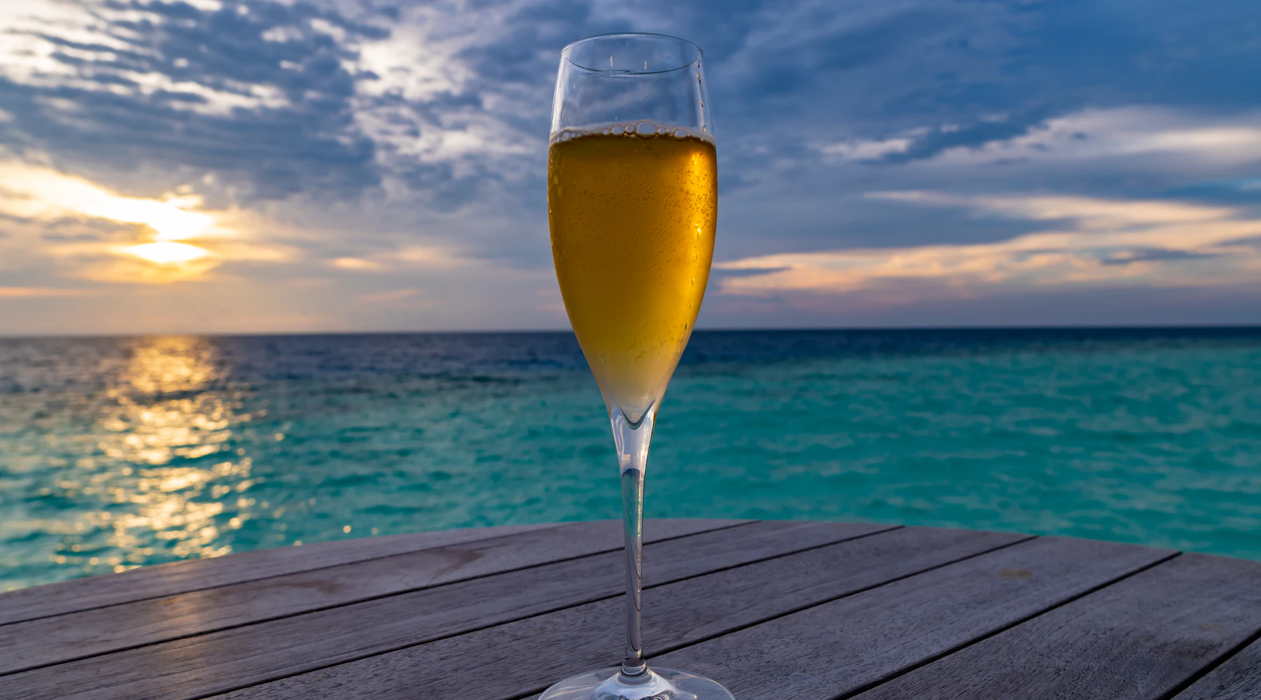 Calice di spumante al tramonto sul mare