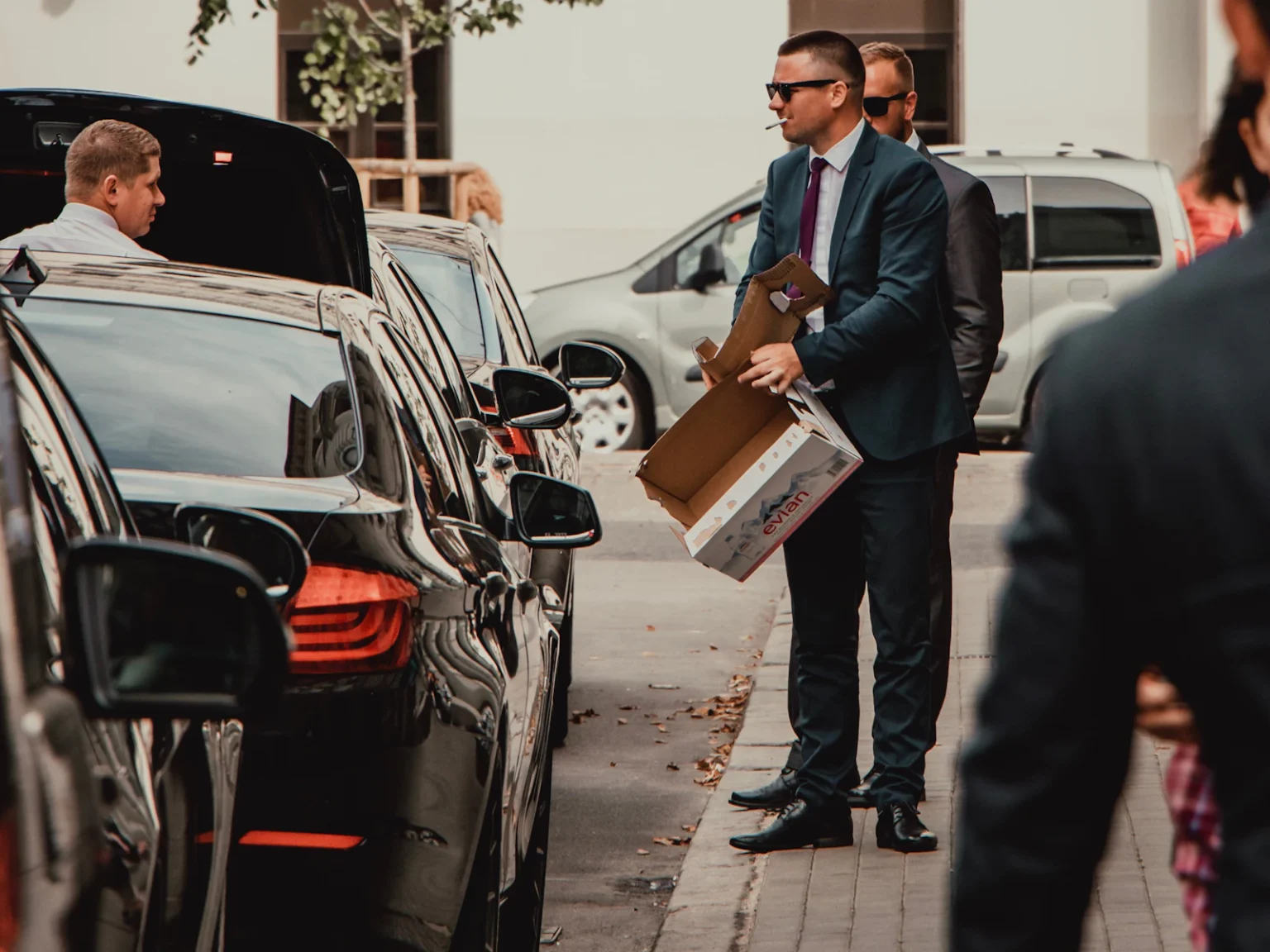 Security officer in a dark suit next to the cars